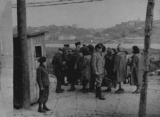 German and Lithuanian guards search a group of Jewish women returning from forced labor outside the Kovno ghetto. Kovno, Lithuania, wartime
